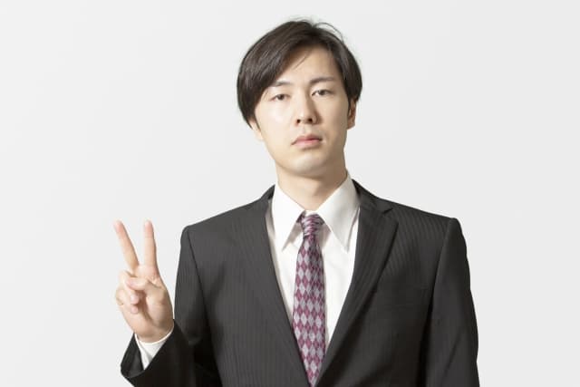 真顔でピースサインをする男性